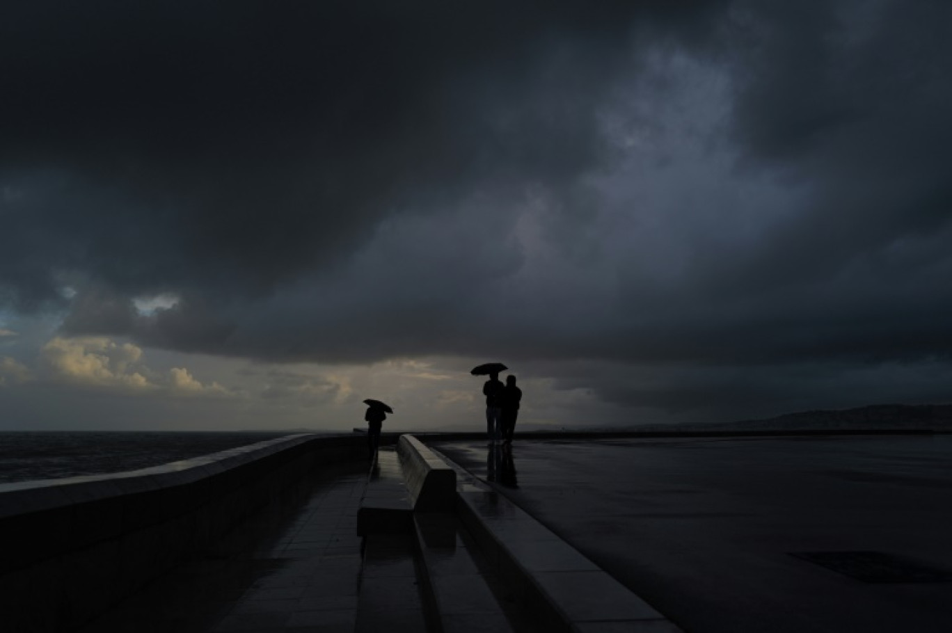 Des gens s'abritent sous un parapluie, le 3 mars 2024 à Nice © Valery HACHE