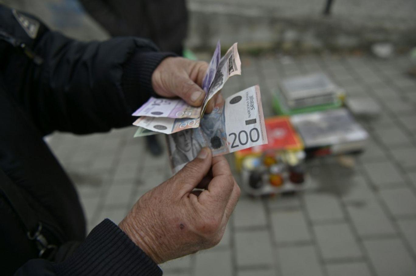 Un vendeur ambulant montre des billets de dinars serbes à Gracanica, le 1er mars 2024 au Kosovo © Armend NIMANI