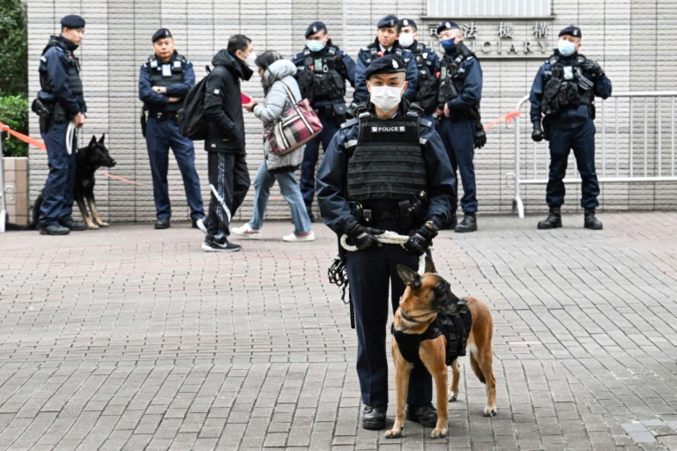 Des policiers accompagnés de chiens montent la garde devant le tribunal de West Kowloon à Hong Kong, le 22 décembre 2023 © Peter PARKS