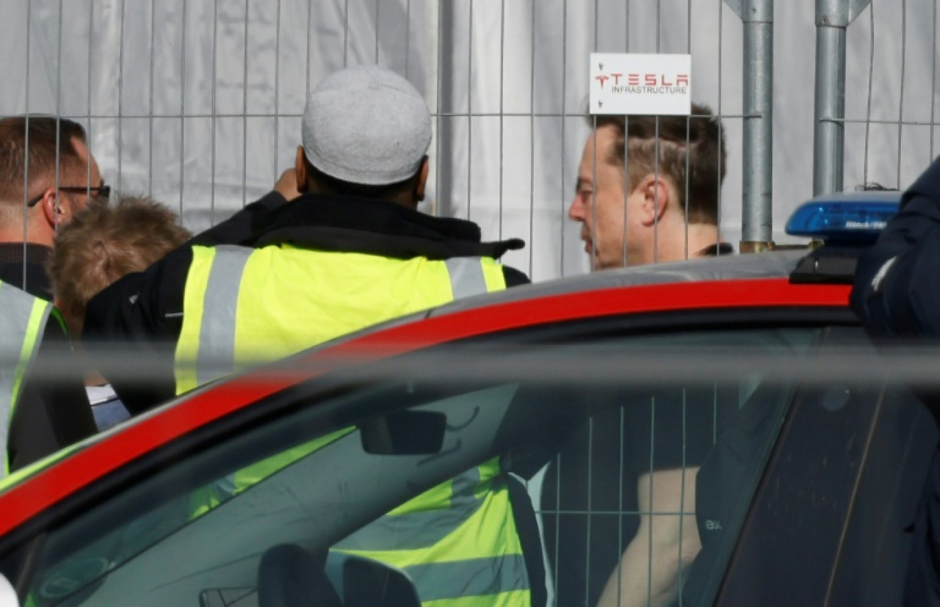 Le patron de Tesla Elon Musk (d) arrive à l'usine Tesla de Grünheide, près de Berlin, une semaine après un sabotage qui a entraîné l'arrêt de la production, le 13 mars 2024 © Odd ANDERSEN