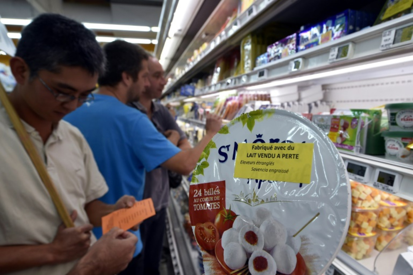 Des agriculteurs posent des étiquettes "Fabriqué avec du lait vendu à perte" sur un produit de du groupe agroalimentaire Savencia dans une grande surface de Rodez, en Aveyron, le 18 août 2015 © PASCAL PAVANI