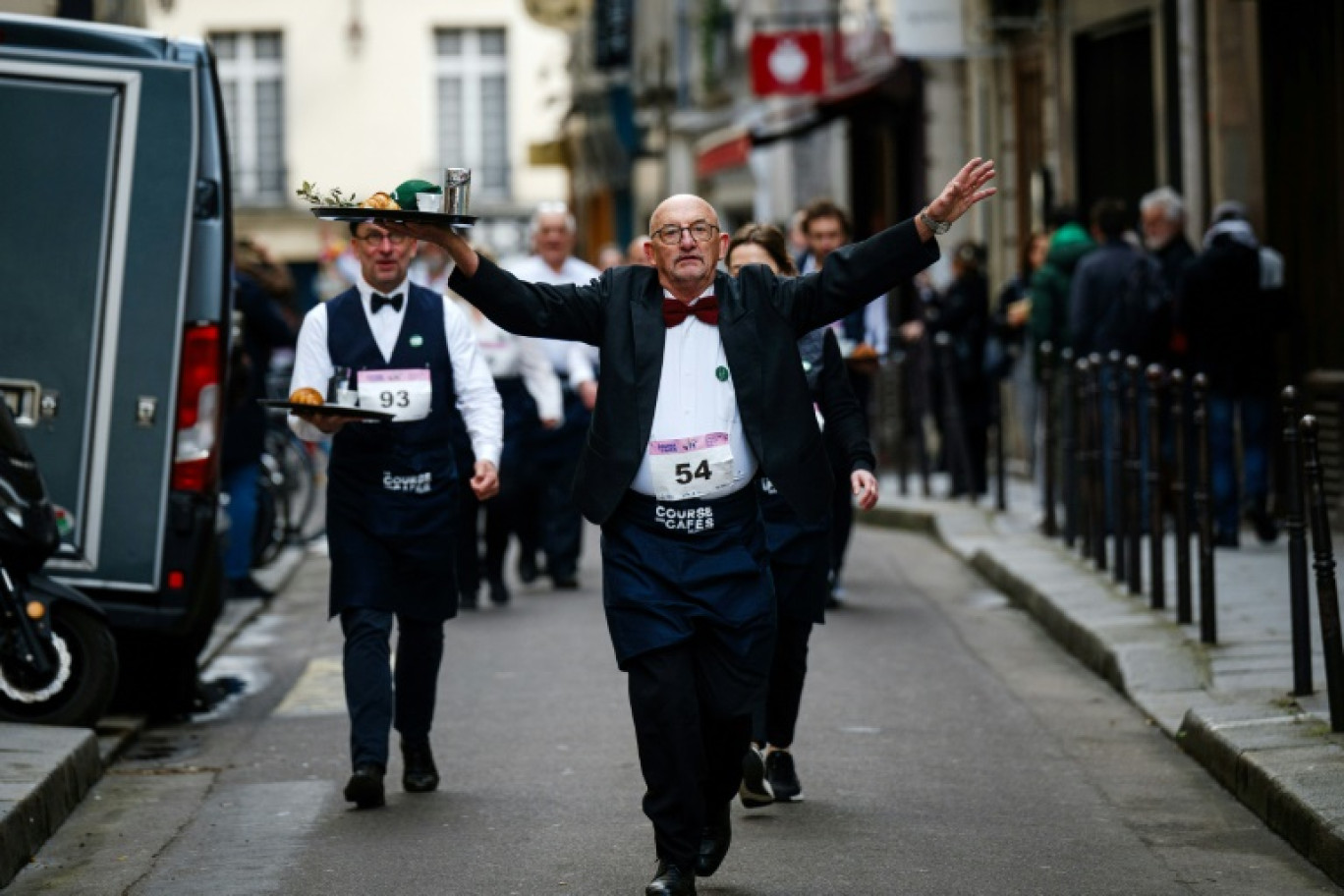 Des serveurs en tenue de travail participent à la traditionnelle "Course des garçons de café", dans le centre de Paris, le 24 mars 2024 © Dimitar DILKOFF