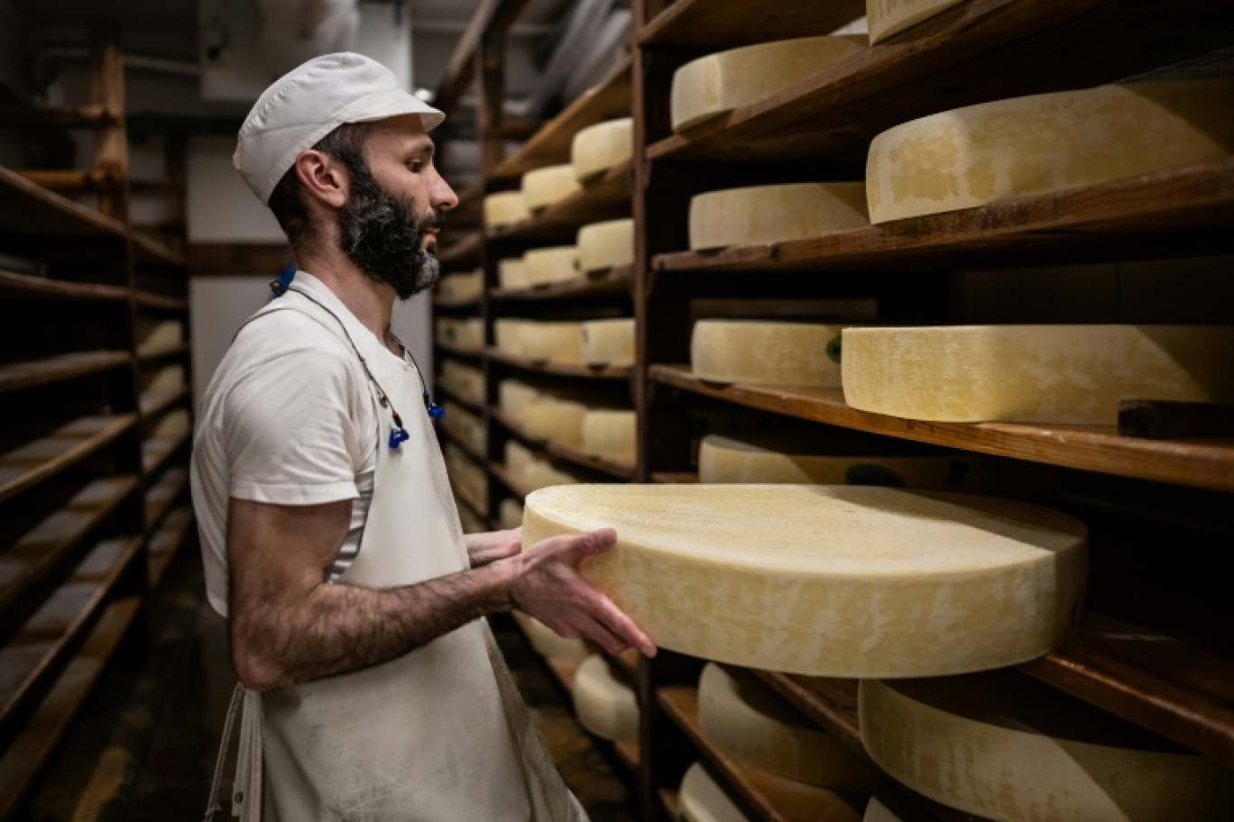 Un employé retourne les meules de Comté à Arc-sous-Cicon, dans le Doubs, le 20 mars 2024 © ARNAUD FINISTRE