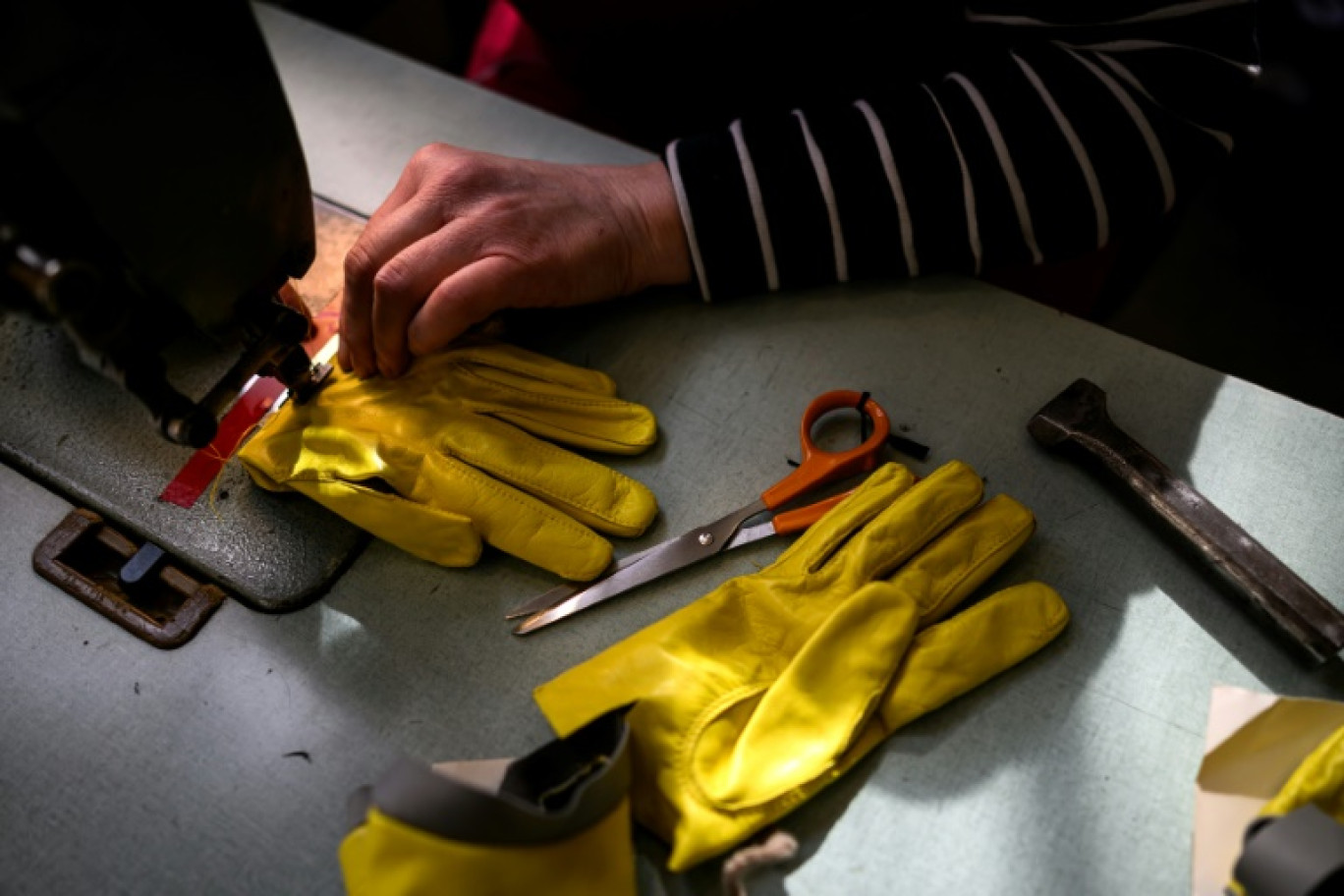 Une employée travaille sur une paire de gants dans l'atelier de La Maison Fabre à Millau, le 15 mars 2024 dans l'Aveyron © Lionel BONAVENTURE