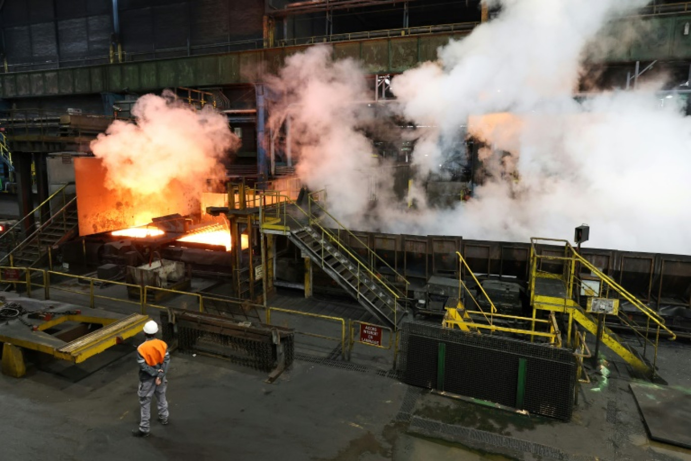 En six ou sept passages sous les rouleaux et les jets d'eau, la barre de métal en fusion de 25 centimètres d'épaisseur s'aplatit et s'allonge en un long et fin ruban d'acier qui servira à fabriquer la torche olympique, dans le laminoir d'ArcelorMittal à Florange, le 4 avril 2024  © FREDERICK FLORIN