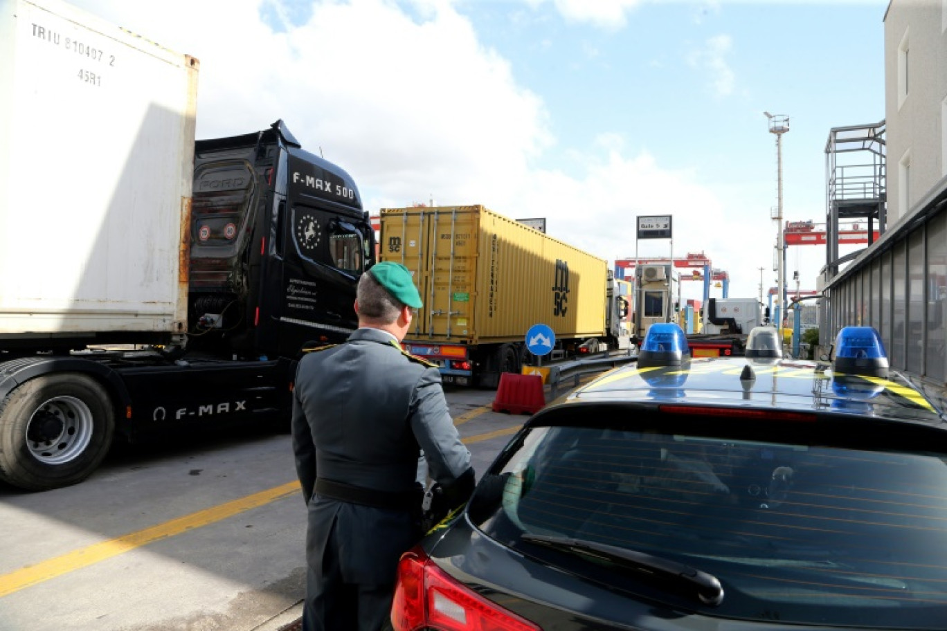 Un officier de la Guardia di Finanza, la police italienne chargée de la criminalité financière et de la contrebande, observent des camions dans la zone commerciale du port de Naples, le 29 février 2024 © CARLO HERMANN