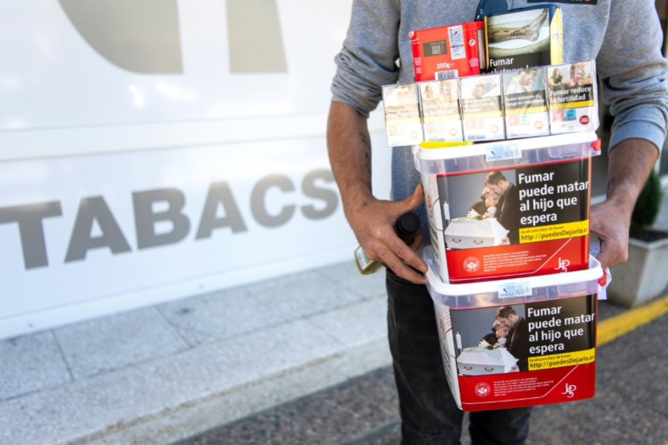 Un hommes porte des paquets de tabac achetéd dans une boutique de Les, en Espagne, le 19 avril 2024 © Matthieu RONDEL