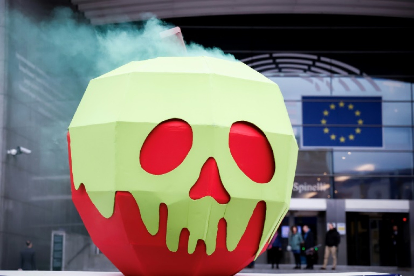 Une installation représentant "une pomme empoisonnée" lors d'une manifestation devant le Parlement européen, le 11 avril 2024 à Bruxelles © Kenzo TRIBOUILLARD