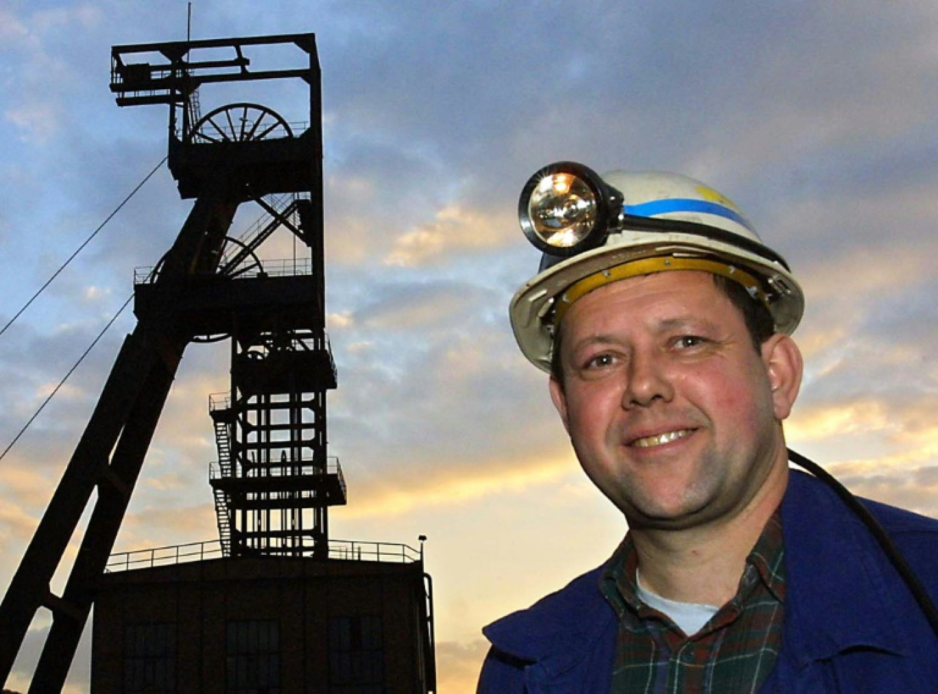 Un mineur pose devant un des chevalements de la mine de La Houve, dernière mine de charbon encore en activité en France, à Creutzwald, en Moselle, le jour de la fermeture du site, le 23 avril 2004 © JEAN-CHRISTOPHE VERHAEGEN