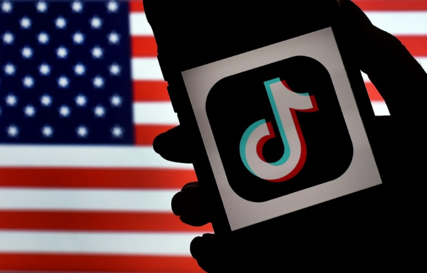 Le logo de TikTok sur un téléphone, avec un drapeau américain en fond, le 3 août 2020 à Arlington © Olivier DOULIERY