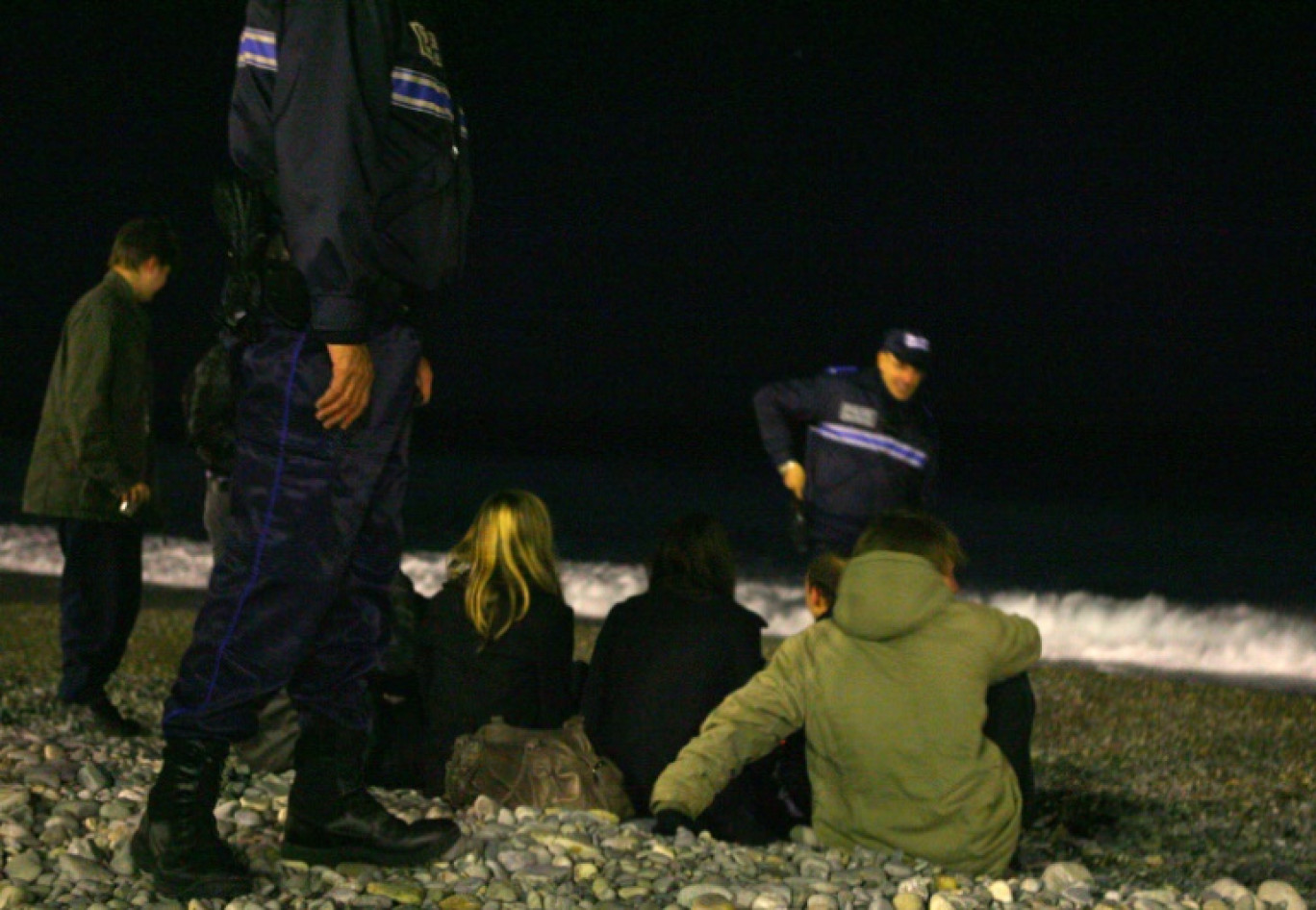 Des policiers parlent avec des jeunes sur la plage à Nice, où le maire a ordonné un couvre-feu nocturne pour les enfants de moins de 13 ans, le 4 décembre 2009 © STEPHANE DANNA