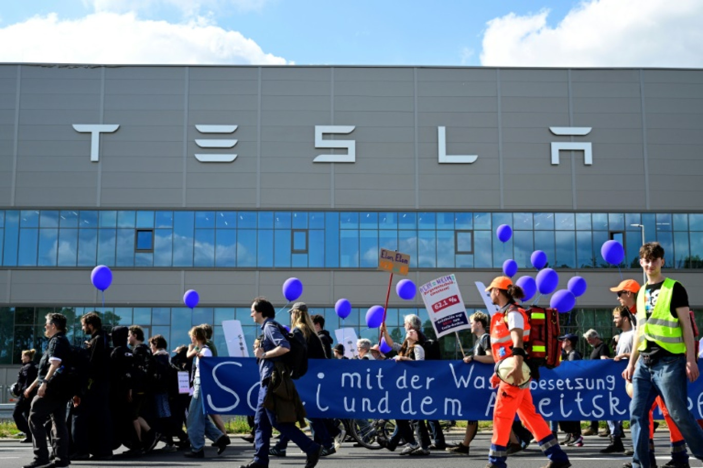 Des manifestants écologistes défilent devant l'usine de Tesla à Grünheide (près de Berlin, en Allemagne) pour protester contre un projet d'agrandissement, le 11  mai 2024 © JOHN MACDOUGALL