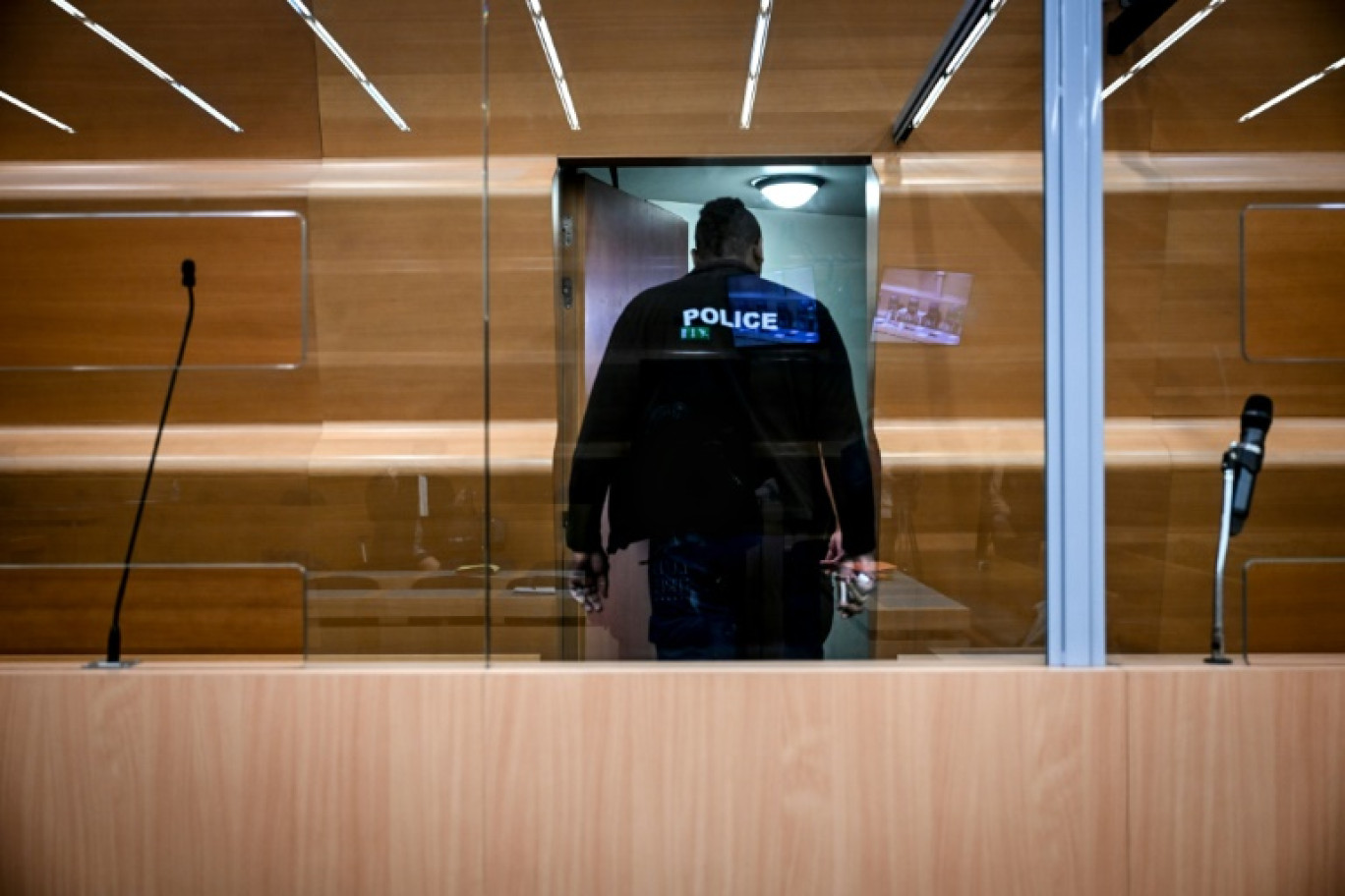 Un policier inspecte le box des accusés dans la salle d'audience du tribunal de Grenoble avant le procès en appel de Gabriel Fortin devant la Cour d'assises de l'Isère, le 13 mai 2024 © OLIVIER CHASSIGNOLE