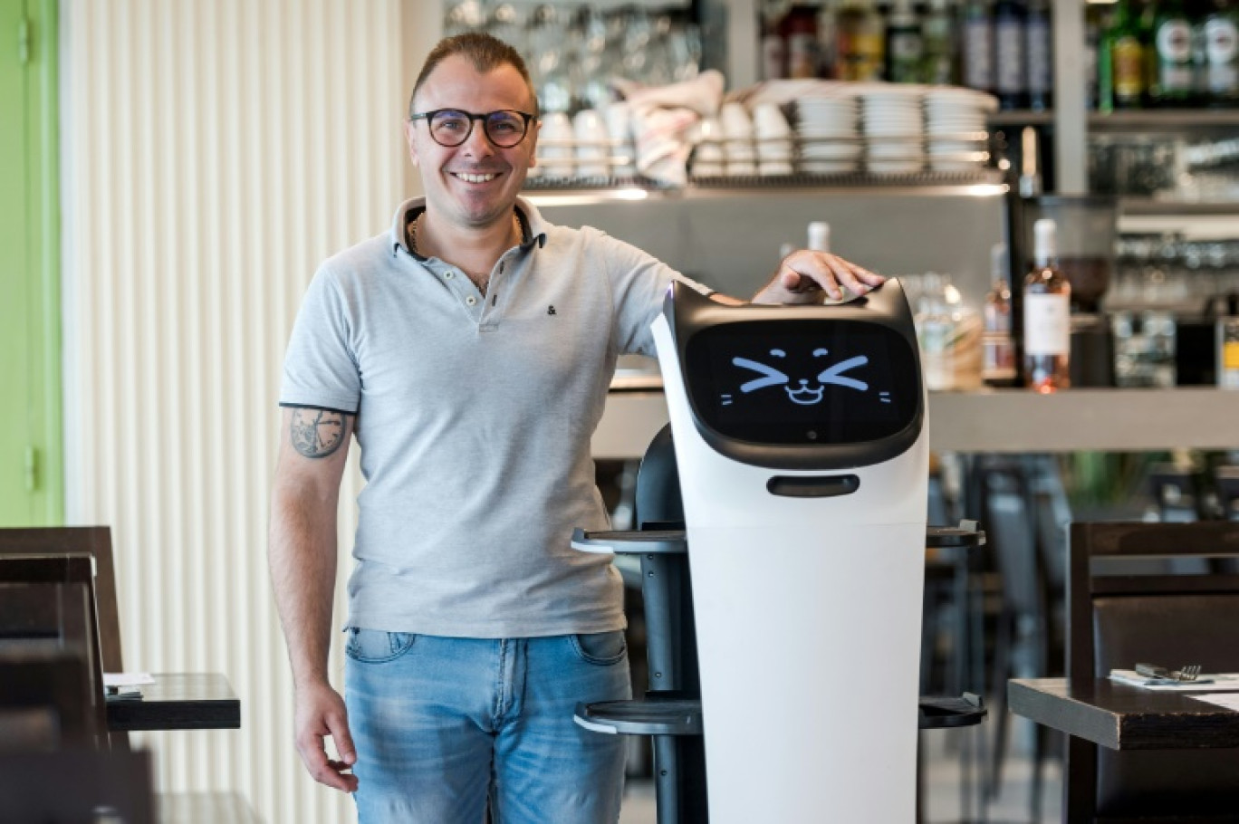 Geoffrey Ruamps, directeur du restaurant le Cap 180, pose avec le robot serveur "Bella" dans son restaurant, à Cieurac, dans le Lot, le 14 mai 2024 © Matthieu RONDEL