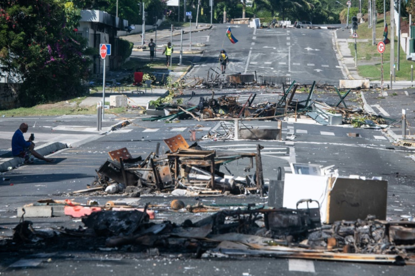 Des habitants font la queue pour acheter des provisions dans un supermarché, à côté des restes incendiés des incidents de la nuit, dans le quartier de Magenta à Nouméa, en Nouvelle Calédonie le 18 mai 2024 © Delphine Mayeur