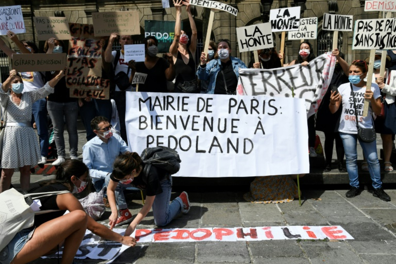 Des femmes tiennent une pancarte "Mairie de Paris: Bienvenue à pédoland" lors d'une manifestation organisée par l'organisation féministe “Nous Toutes” devant l'hôtel de ville de Paris, le 23 juillet 2020, pour protester contre la nomination de Christophe Girard comme adjoint à la maire de Paris © Bertrand GUAY