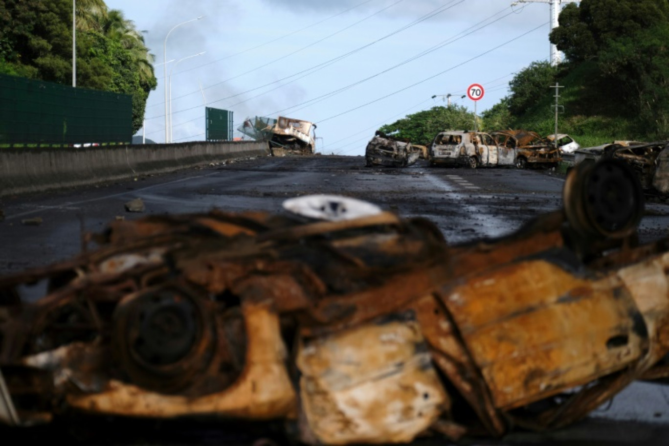 Des véhicules incendiés gisent sur une route menant à Nouméa, dans le territoire français de Nouvelle-Calédonie, le 20 mai 2024 © Theo Rouby