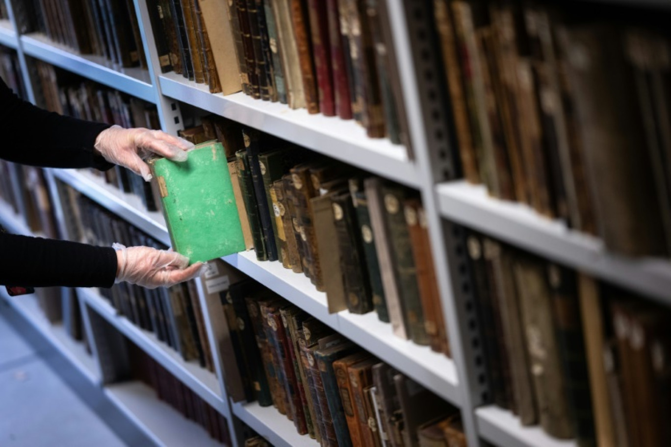 Aude Therstappen, conservatrice de la BNU (Bibliothèque nationale et universitaire) à Strasbourg, retire des réserves un livre coloré en vert avec l'arsenic, le 17 mai 2024 © SEBASTIEN BOZON