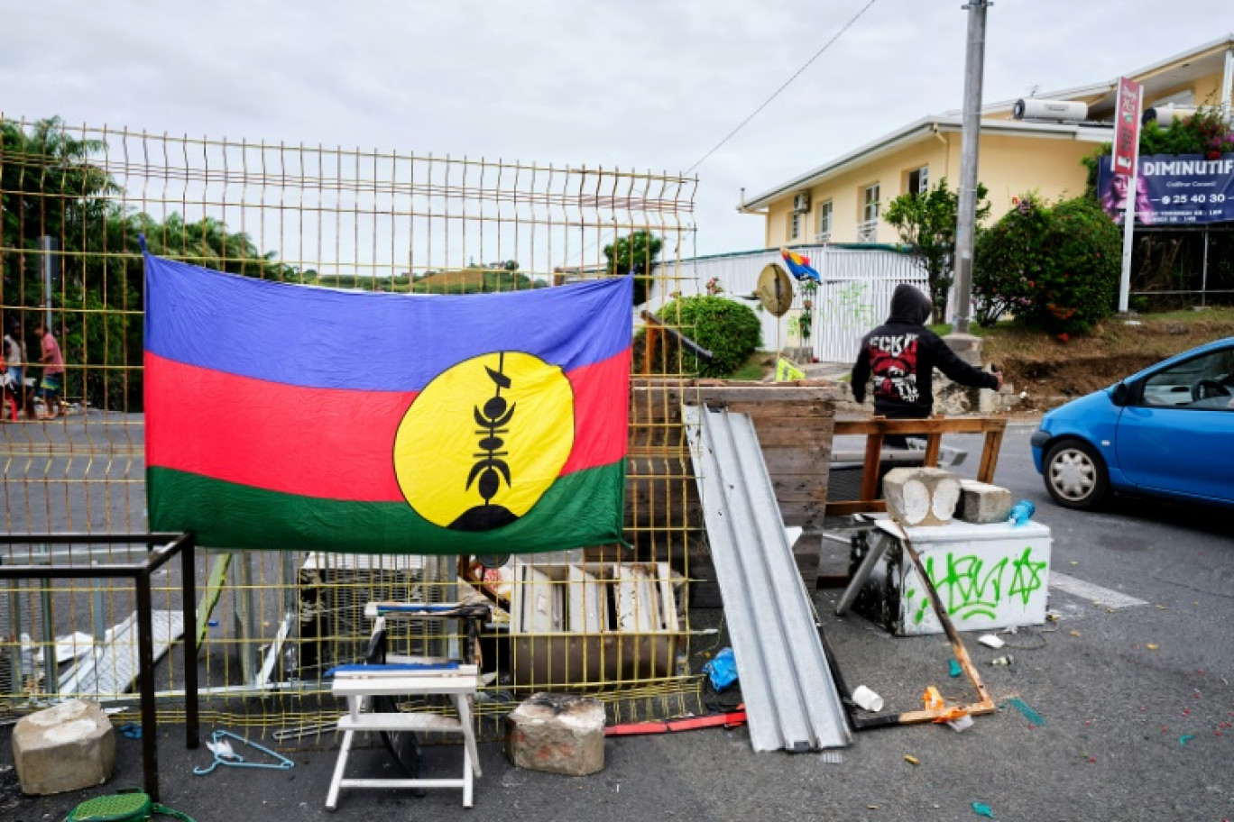 Un drapeau kanak sur un barrage dans le quartier de Magenta, à Nouméa, où un manifestant régule la circulation, le 22 mai 2024 en Nouvelle-Calédonie © Theo Rouby