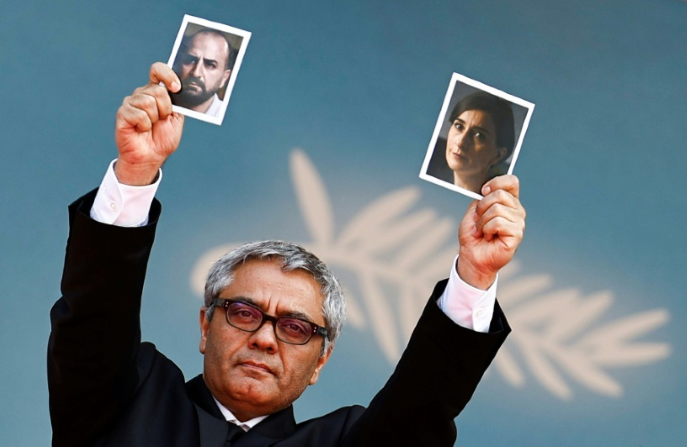 Iranian director Mohammad Rasoulof holds a portrait of Iranian actress Soheila Golestani  (R) and Iranian actor Missagh Zareh (L) as he arrives for the screening of the film "The Seed of the Sacred Fig" at the 77th edition of the Cannes Film Festival in Cannes, southern France, on May 24, 2024. © Sameer Al-Doumy