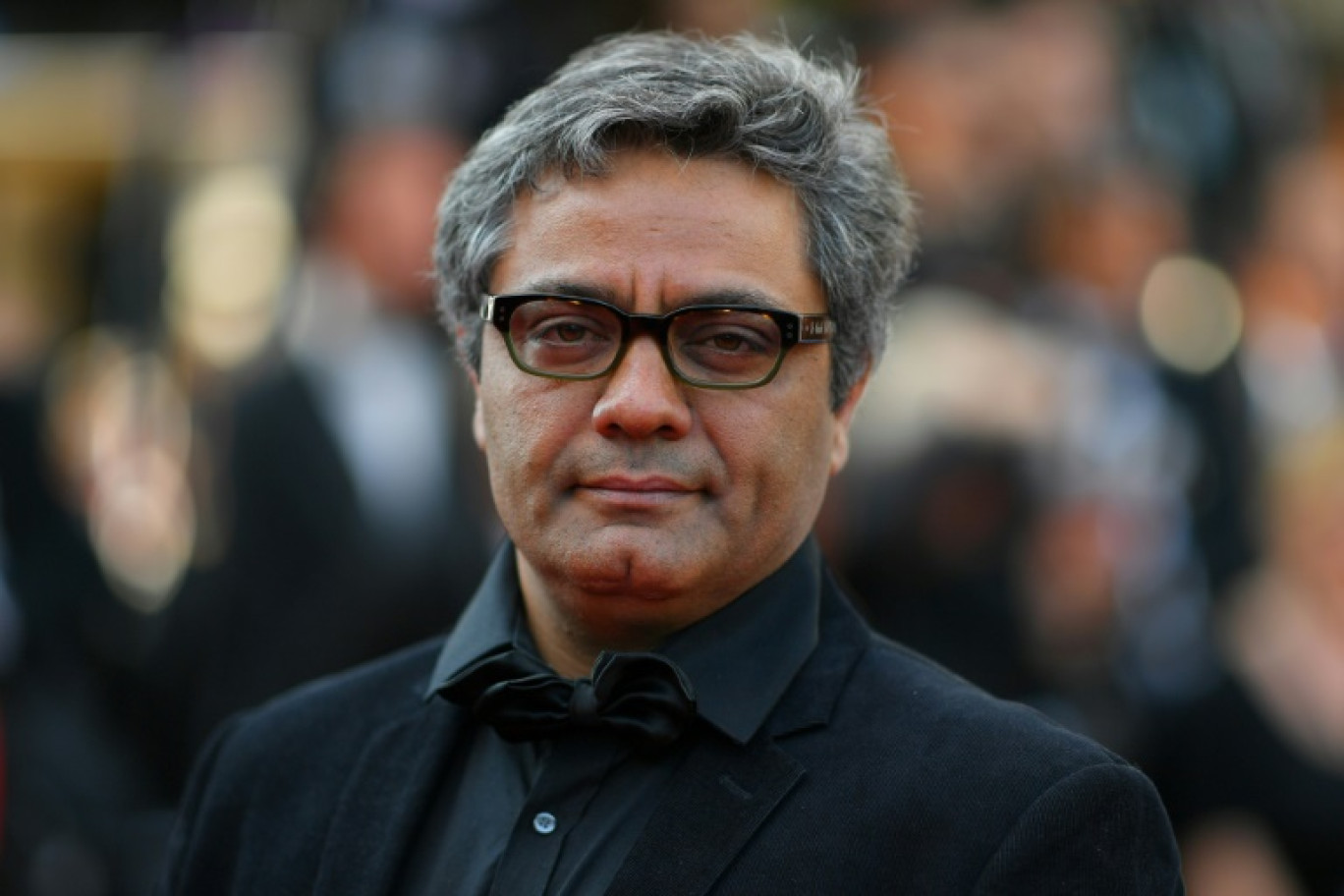 Le réalisateur iranien Mohammad Rasoulof brandit les photos de l'acteur iranien Missagh Zareh, à gauche, et de l'actrice iranienne Soheila Golestani, à droite, le 24 mai 2024, au festival de Cannes, dans les Alpes-Maritimes © Sameer Al-Doumy