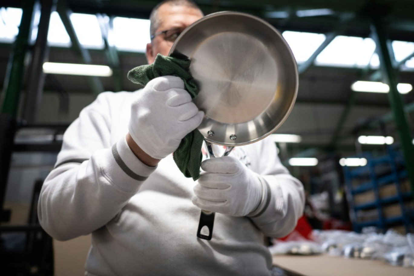 Un employé nettoie une poêle en inox dans l'usine Cristel à Fesches-le-Chatel, dans le Doubs, le 23 mai 2024 © SEBASTIEN BOZON