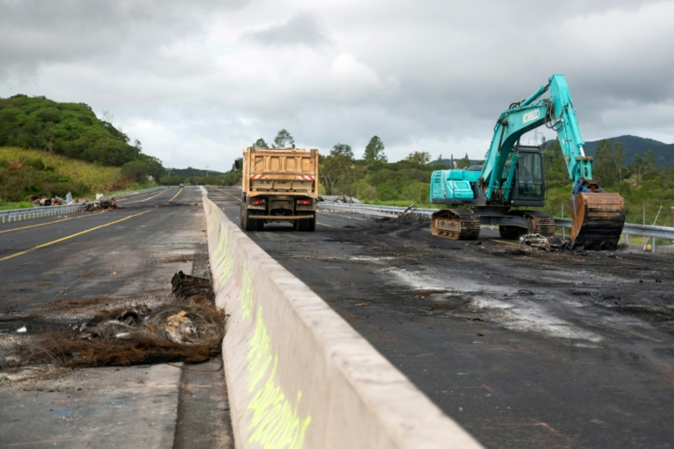 Des engins de chantier enlèvent des débris sur la route RT1 qui mène à l'aéroport international de Nouméa, le 19 mai 2024 © Delphine Mayeur