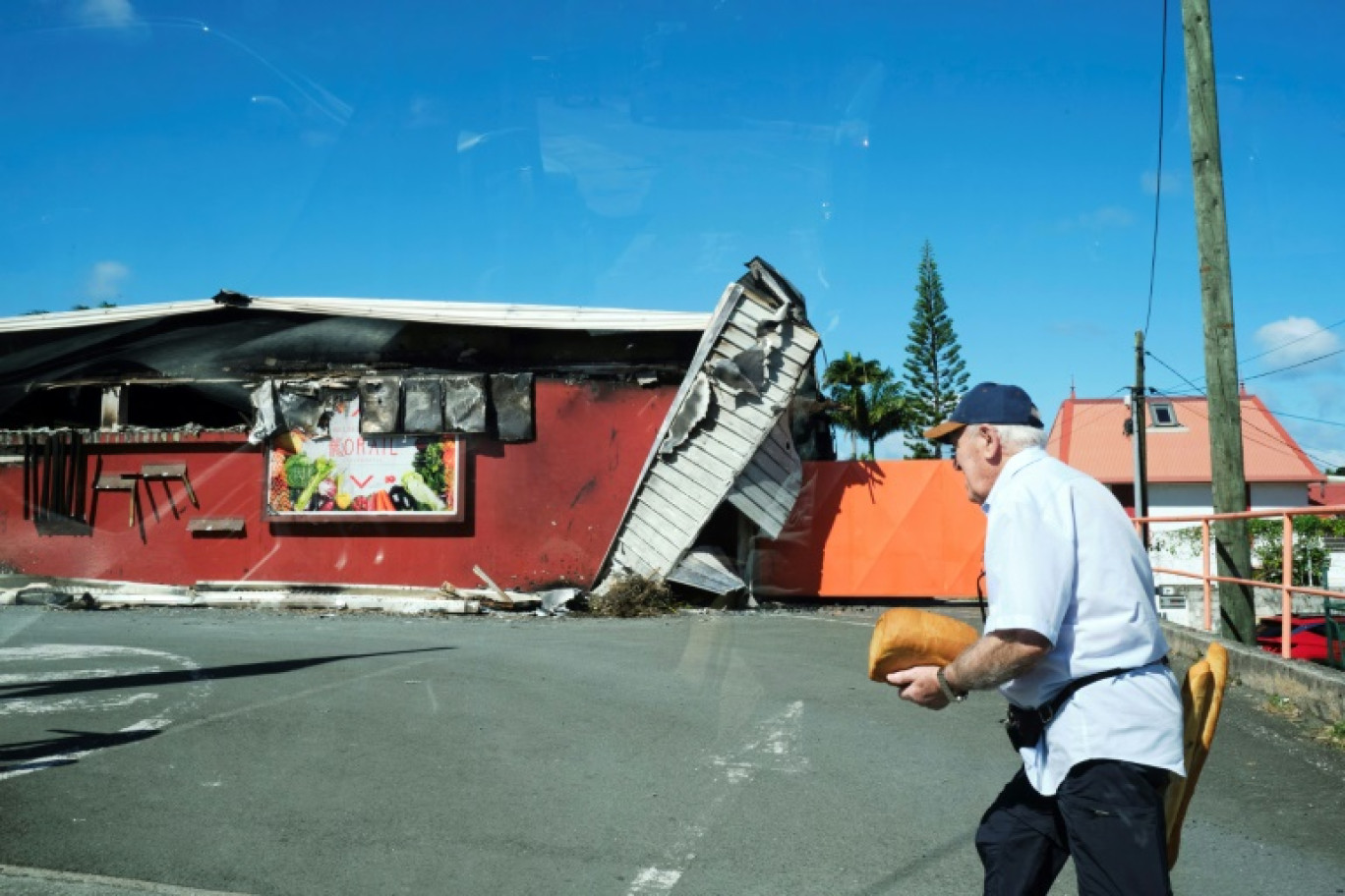 Un homme passe devant un supermarché endommagé à Nouméa, en Nouvelle-Calédonie, le 24 mai 2024 © Theo Rouby