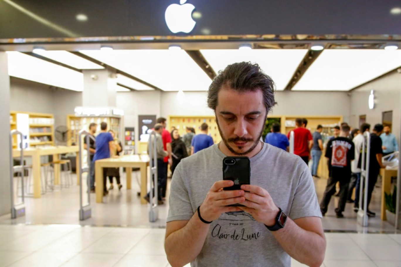 Un homme est sur son iPhone devant une boutique Apple située dans un centre commercial à Téhéran, le 28 mai 2024 © -