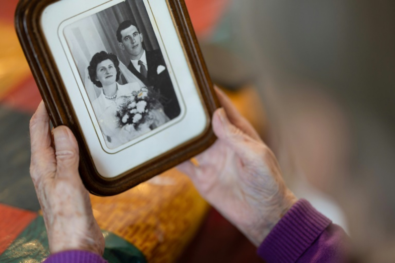 Jeanne Tournellec regarde la photo de mariage de sa sœur Catherine Tournellec, violée par un soldat américain, et de son beau-frère Jean Salaun, chez elle à Locmaria-Plouzane, le 14 mars 2024 dans  le Finistère © Fred TANNEAU