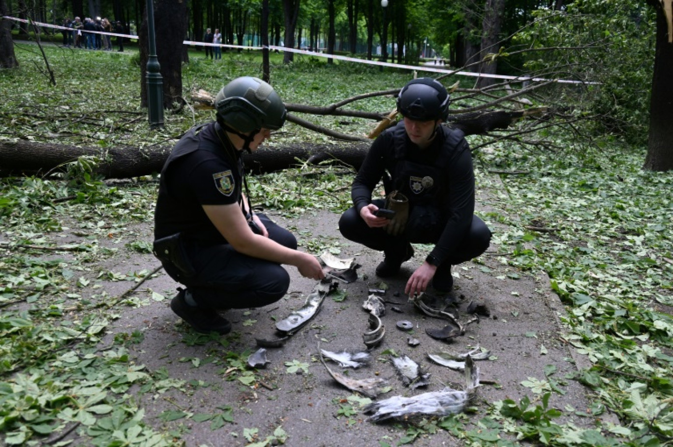 Des policiers ukrainiens examinent des fragments d'un missile dans un parc de Kharkiv le 19 mai 2024 © SERGEY BOBOK