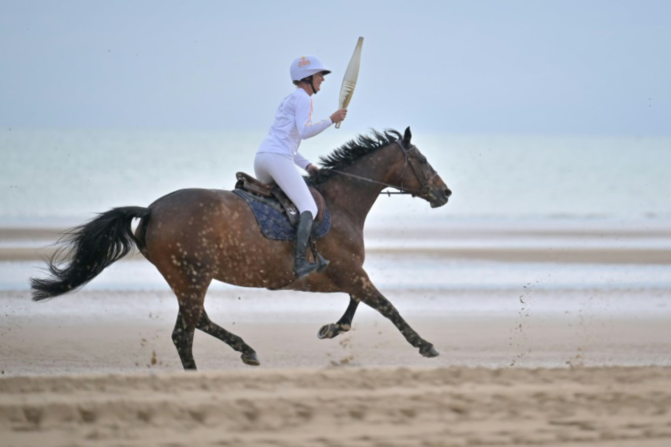 La cavalière Pénélope Leprévost, au galop sur la plage d'Omaha Beach, porte la flamme olympique, le 30 mai 2024 à Saint-Lauren-sur-Mer, dans le Calvados © LOU BENOIST