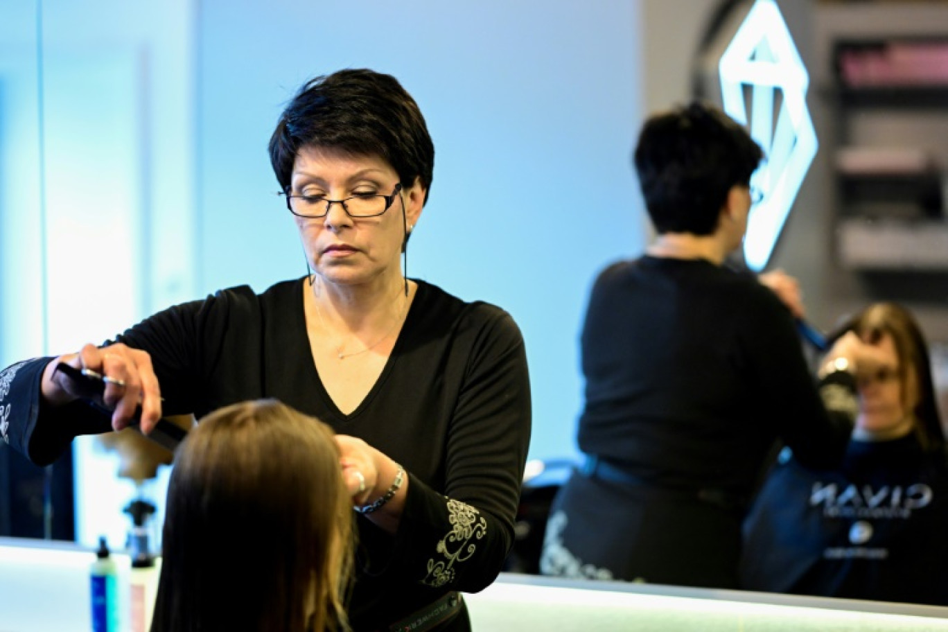 La coiffeuse et réfugiée ukrainienne Valentyna Vysotska coupe les cheveux d'une cliente dans un salon à Berlin, le 22 avril 2024 © Tobias SCHWARZ