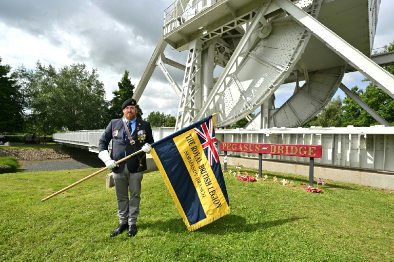 Alisdaire Le Bugle porte le drapeau de la British Legion Normandy devant Pegasus Bridge à Bénouville le 4 juin 2024 © Miguel MEDINA