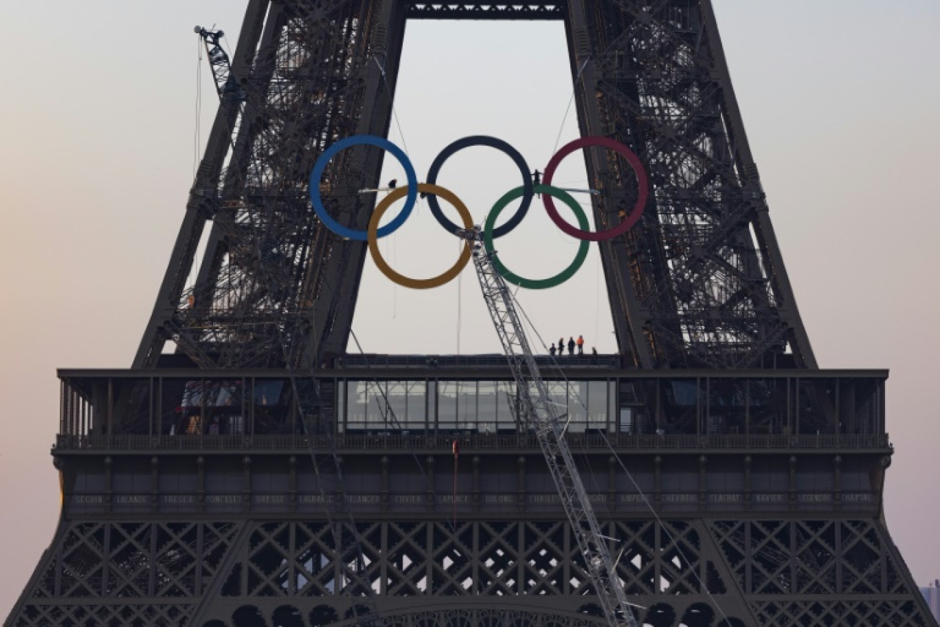 Des équipes finissent d'accrocher les anneaux olympiques à la tour Eiffel, le 7 juin 2024, à Paris © JOEL SAGET