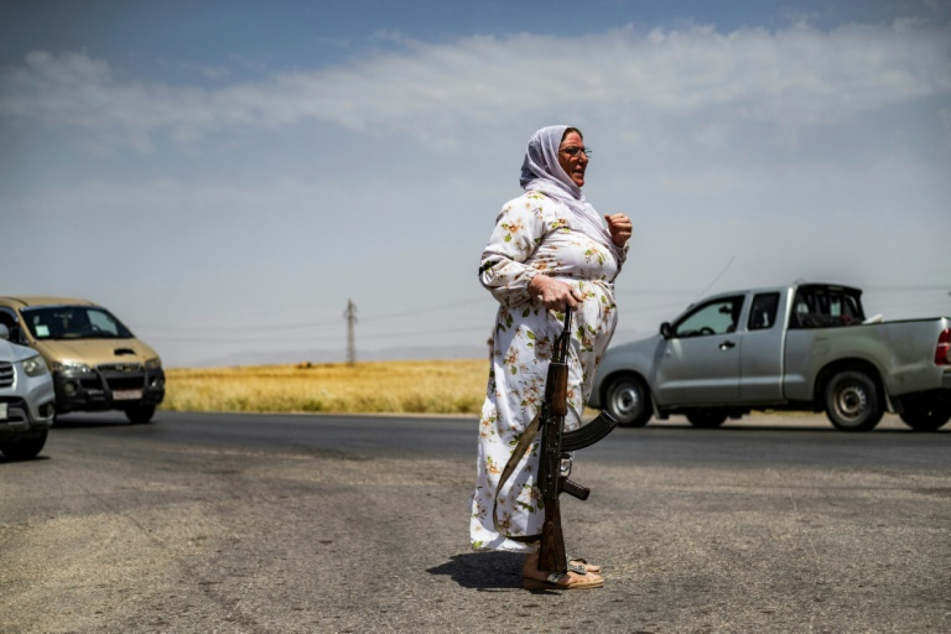 Une volontaire kurde garde un champ de blé près de la localité d'al-Qahtaniyah dans le nord-est de la Syrie, le 30 mai 2024 © Delil SOULEIMAN