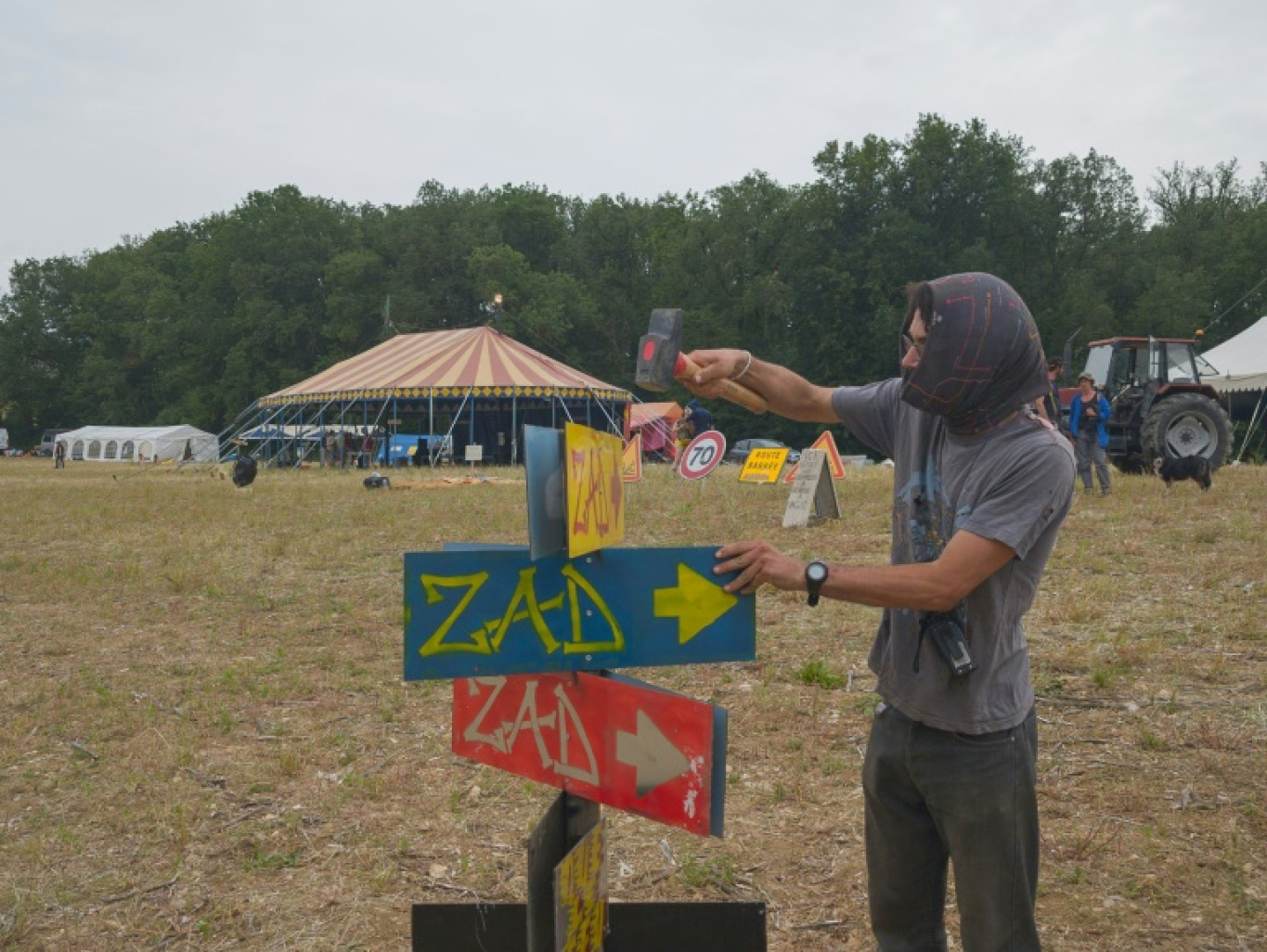 Un manifestant installe des pancartes "ZAD" (Zone à défendre) alors que des militants arrivent à un campement mis en place pour protester contre le projet d'autoroute A69 entre Toulouse et Castres, près de Puylaurens, le 7 juin 2024 dans le Tarn © Ed JONES