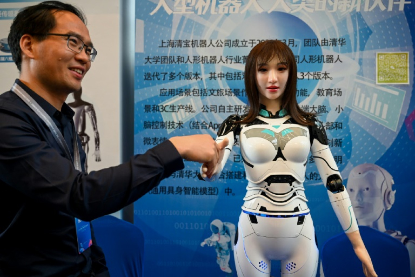 Un exposant serre la main d'un robot humanoïde lors de l'édition 2024 du Salon des concepteurs de robots humanoïdes, à Shanghai (Chine) le 6 juin 2024. © STR