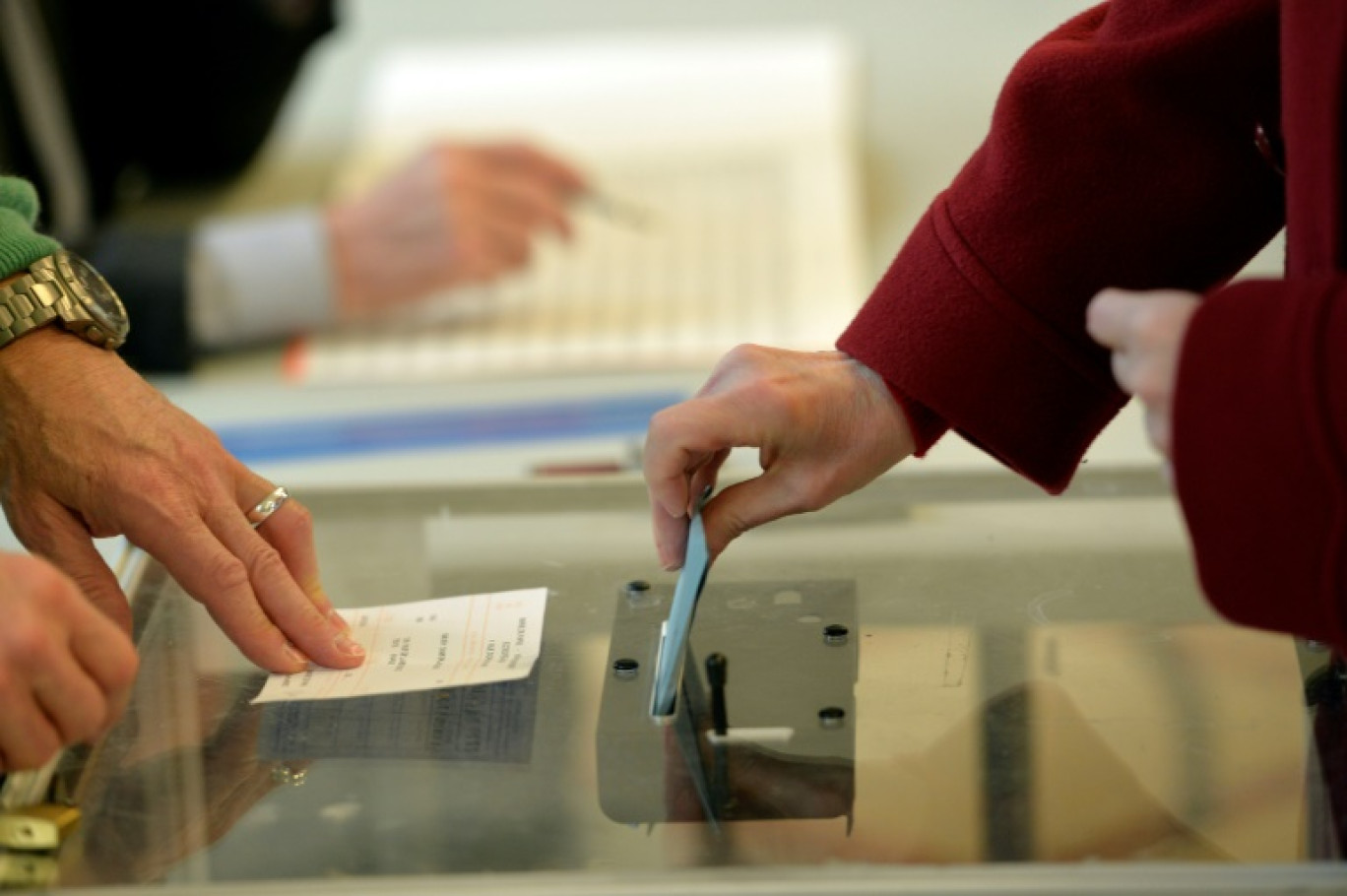 Une femme glisse son bulletin de vote lors du premier tour des élections municipales le 23 mars 2014 à Paris © MIGUEL MEDINA