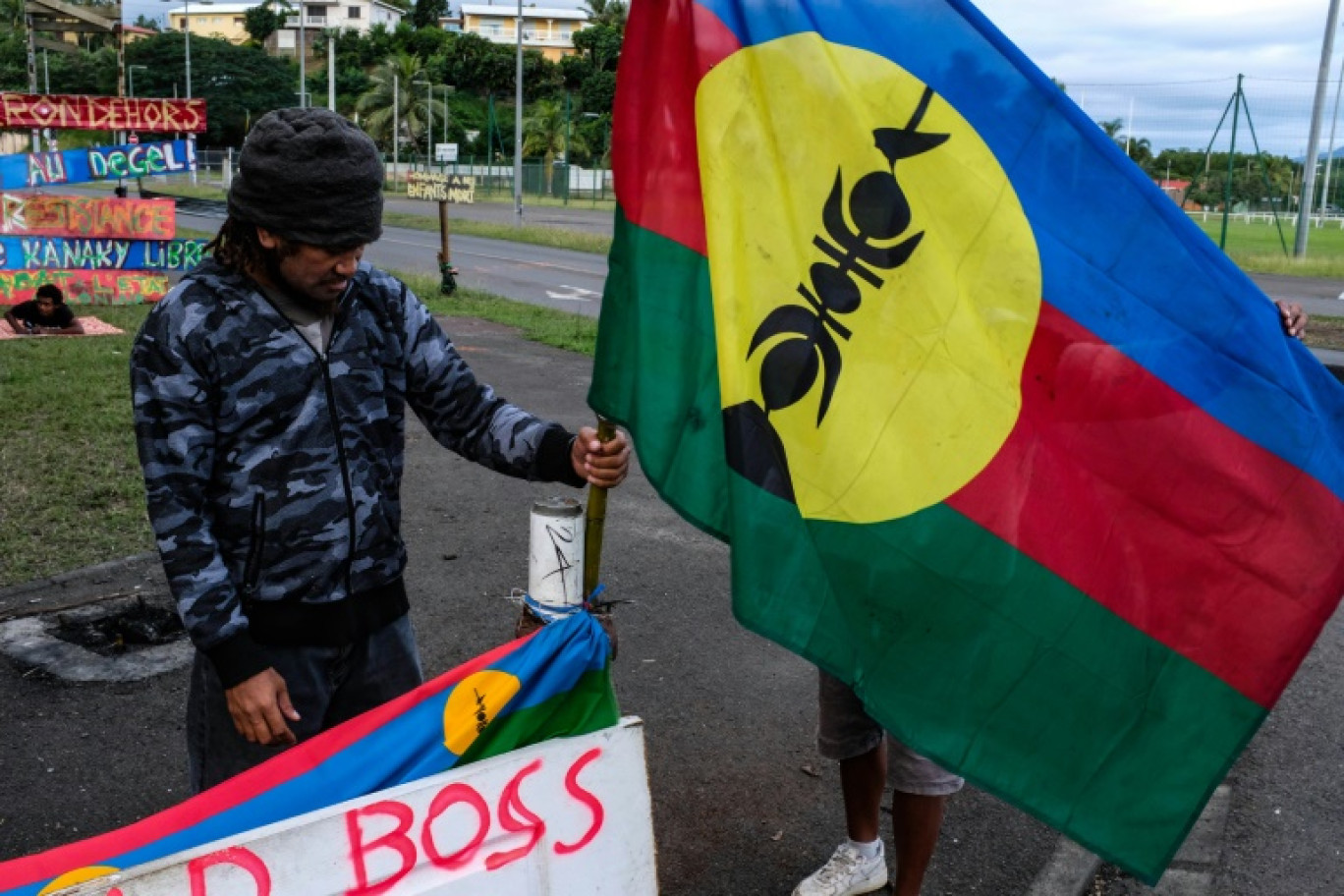 Un homme tient un drapeau kanak sur un campement indépendantiste à Rivière Salée en Nouvelle-Calédonie, le 12 juin 2024 © Thomas BERNARDI