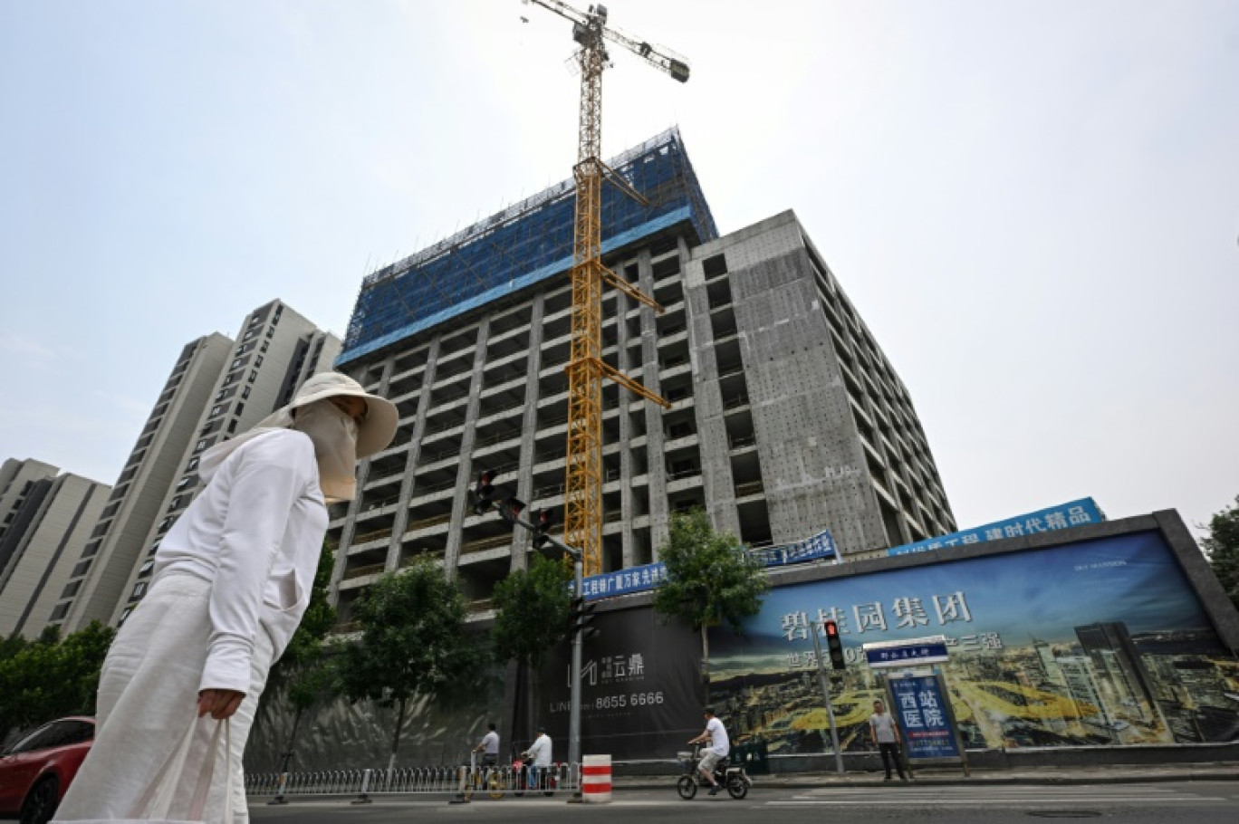 Une femme marche devant une résidence en construction le 5 juin 2024 à Tianjin, dans le nord de la Chine © Jade GAO