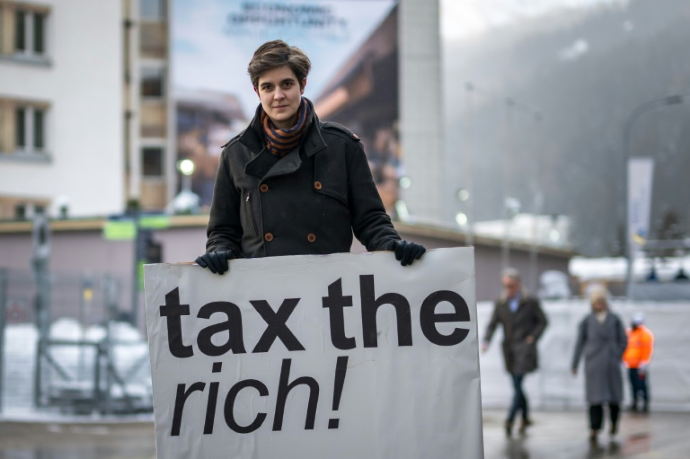 L'Autrichienne Marlene Engelhorn, qui a hérité de sa famille propriétaire du géant allemand de la chimie BASF, tient une pancarte "Taxez les riches !" à l'ouverture du Forum économique mondial (WEF) de Davos, le 15 janvier 2024 en Suisse © Fabrice COFFRINI