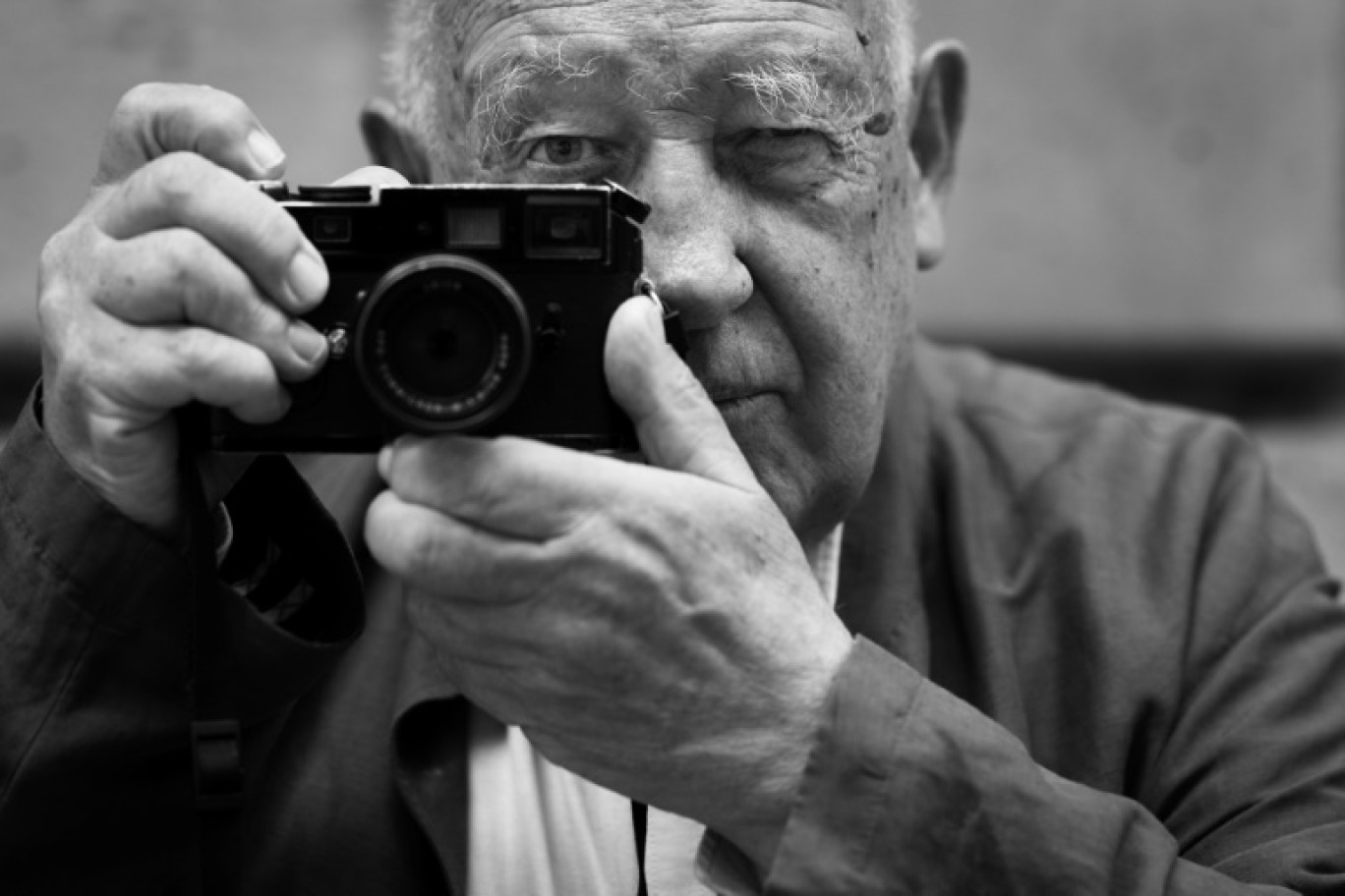 Le photographe français Raymond Depardon pose avec son appareil Leica pendant l'installation, le 24 juin 2024, à Paris, d'une exposition de certaines de ses photographies prises pendant des Jeux olympiques © JOEL SAGET