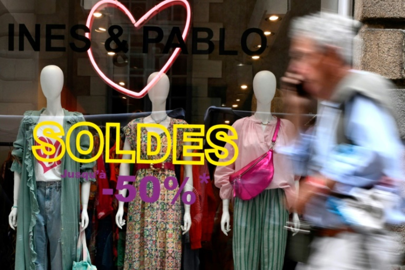 Un homme passe devant une vitrine le premier jour des soldes d'été à Rennes, le 28 juin 2023 © Damien MEYER