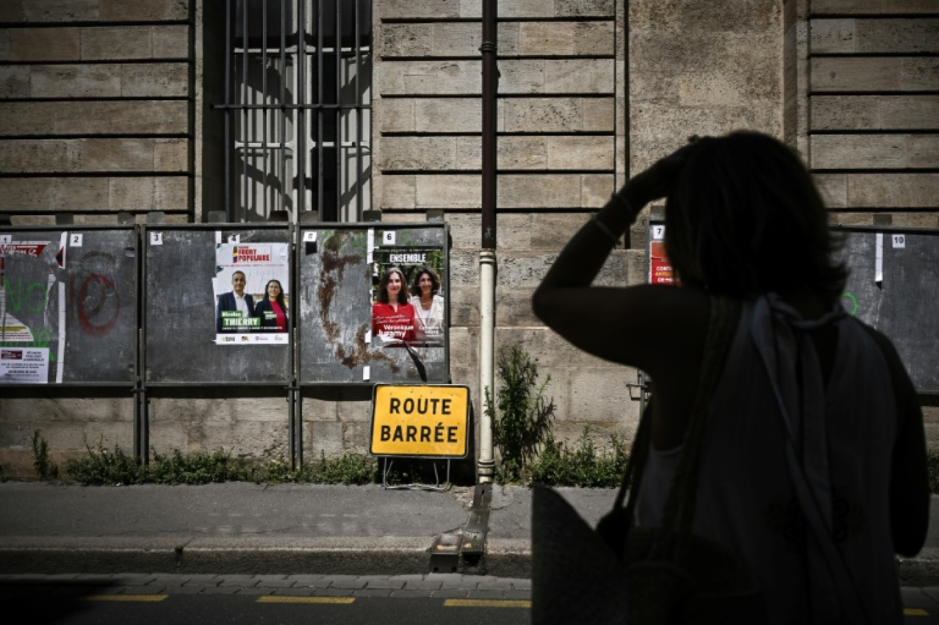 Une femme passe devant des panneaux électoraux avant les législatives à Bordeaux le 25 juin 2024 © Philippe LOPEZ