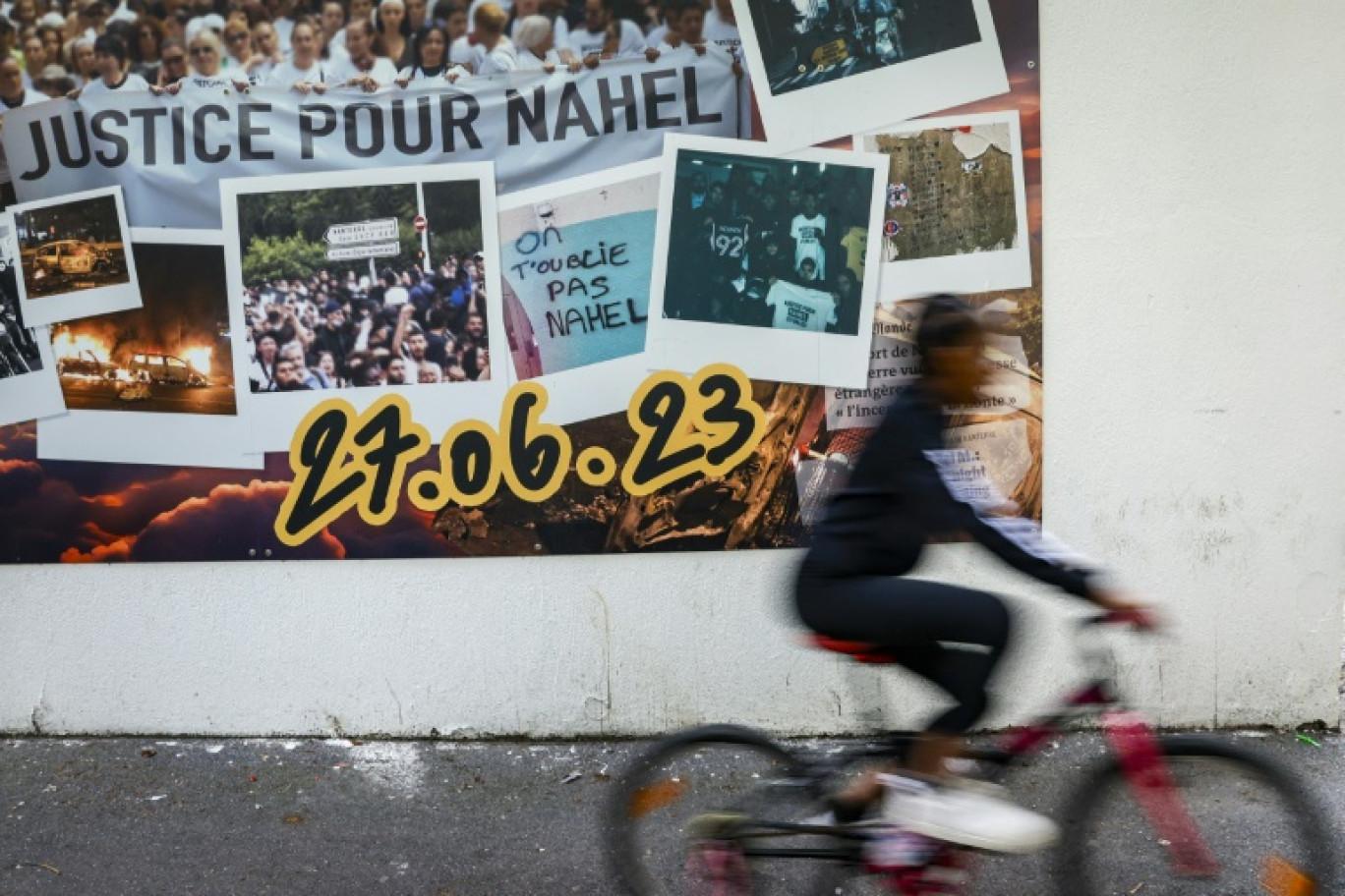 Un cycliste passe, à Nanterre, au nord-ouest de Paris, le 6 juin 2024, devant une fresque en hommage à  Nahel, tué à 17 ans l'an dernier par un policier lors d'un contrôle © Geoffroy VAN DER HASSELT