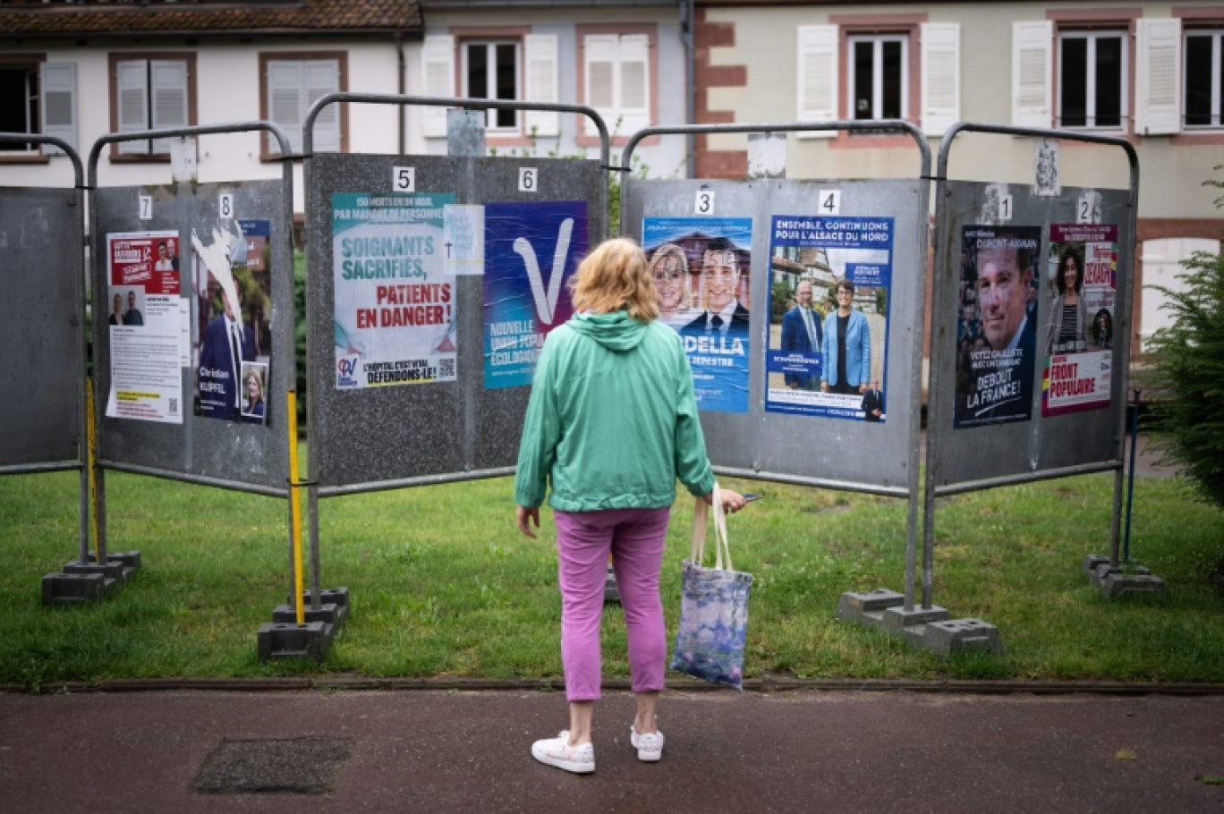 Une femme regarde les affiches électorales des candidats aux législatives à Wissembourg, le 30 juin 2024 dans le Bas-Rhin © SEBASTIEN BOZON