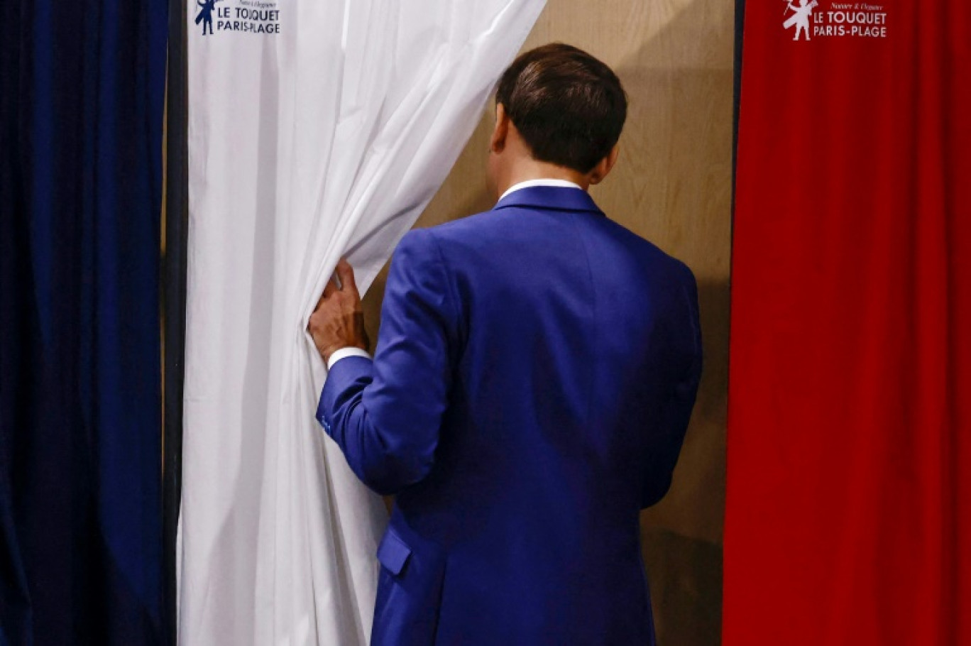 Le président Emmanuel Macron entre dans l'isoloir pour voter au premier tour des élections législatives dans un bureau de vote du Touquet, dans le Pas-de-Calais, le 30 juin 2024 © Yara Nardi