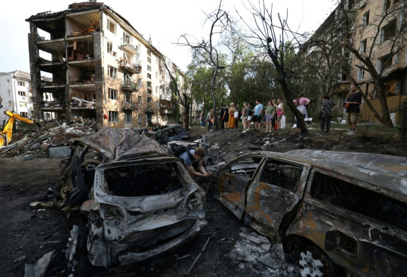 Des habitants se tiennent près de bâtiments et de véhicules touchés par une frappe de missile à Kiev, en Ukraine, le 8 juillet 2024 © Anatolii STEPANOV