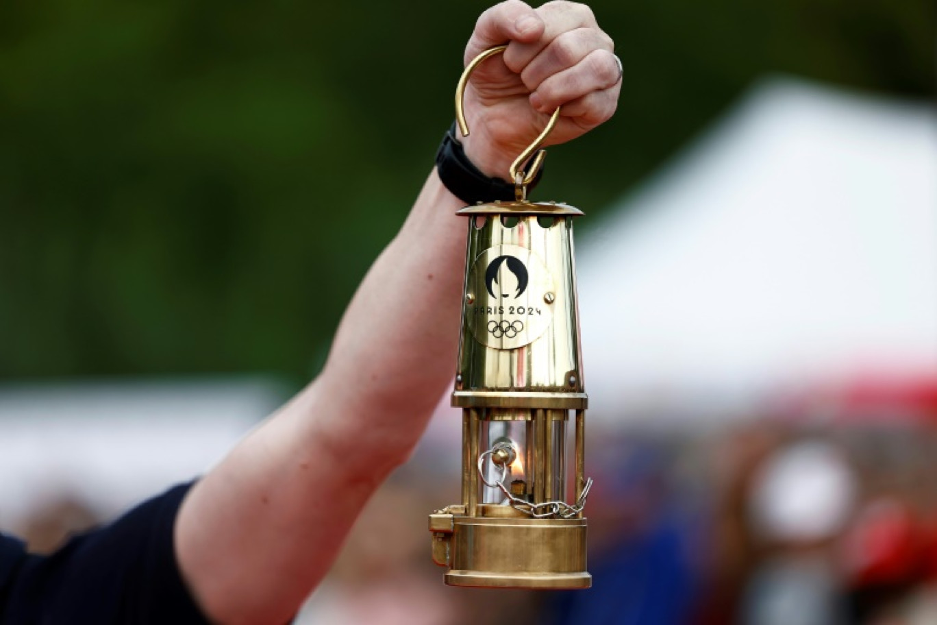 Le cavalier Thibaut Vallette (c), chef des écuyers du Cadre noir de Saumur et médaillé d'or aux JO de Rio en 2016, porte la flamme olympique lors du défilé militaire avenue Foch, le 14 juillet 2024 à Paris © Ludovic MARIN